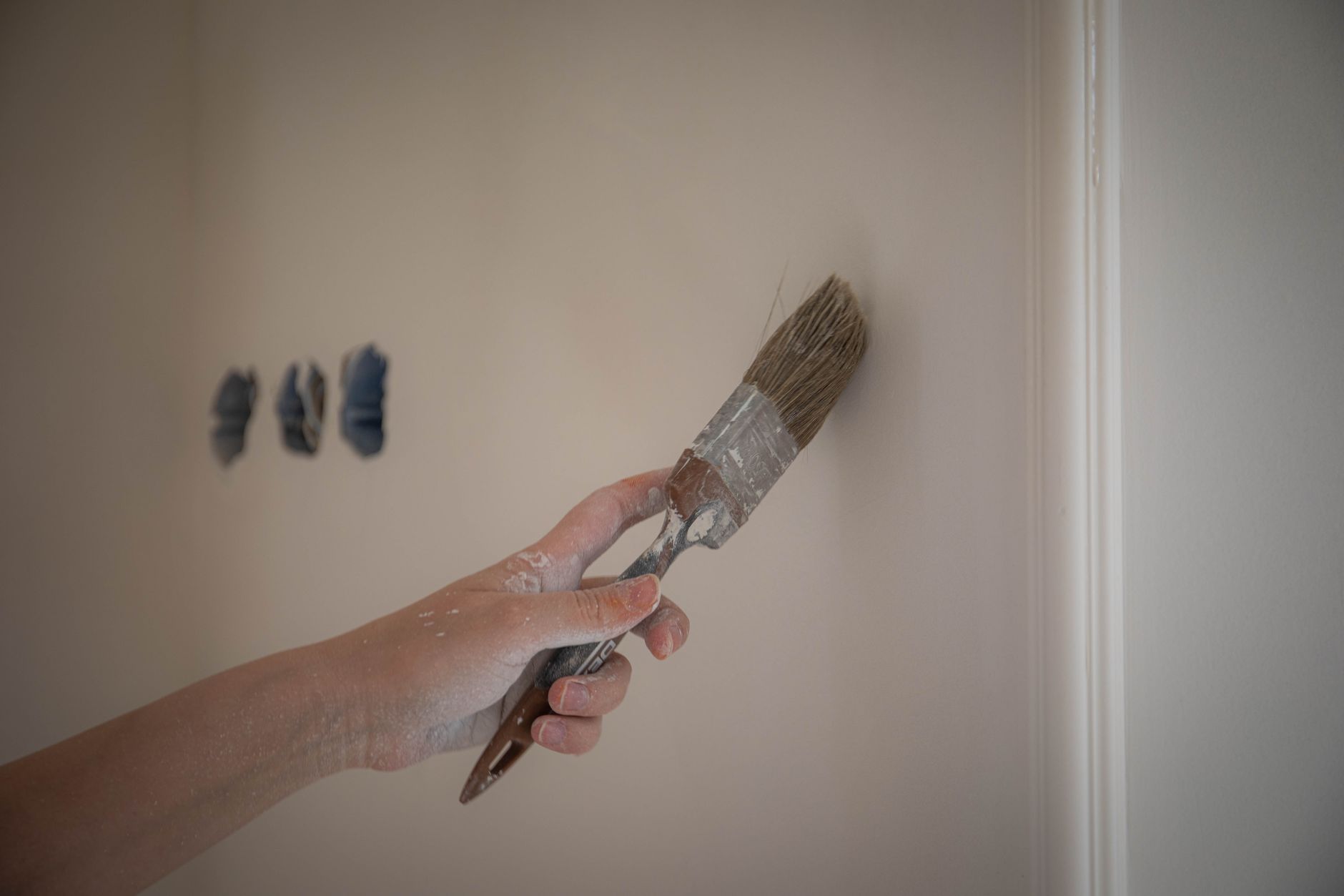 Close-up image of a hand painting a wall with a brush for home renovation in Torrance, CA